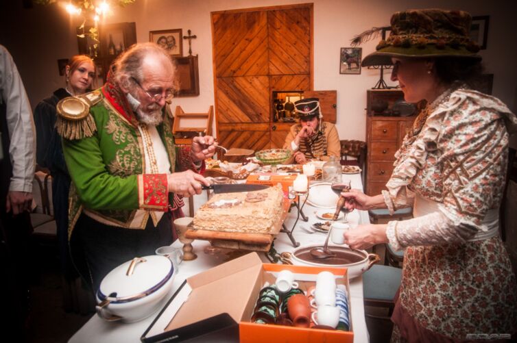 Dámy a páni v odeve z 19teho storočia si naberajú jedlo, podujatie Menzúra